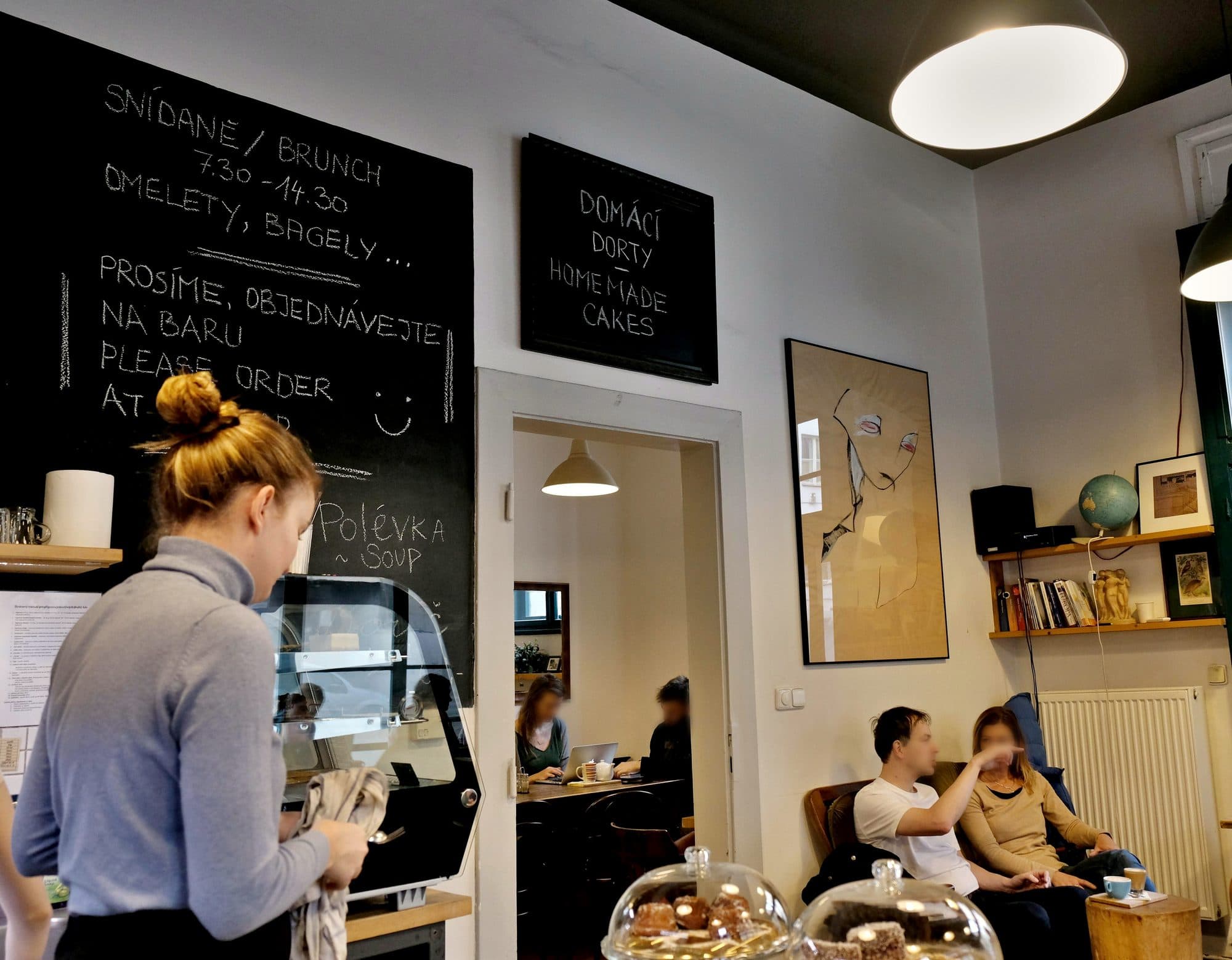 Obsluha u velké křídové tabule se snídaňovým menu v Žižkavárně